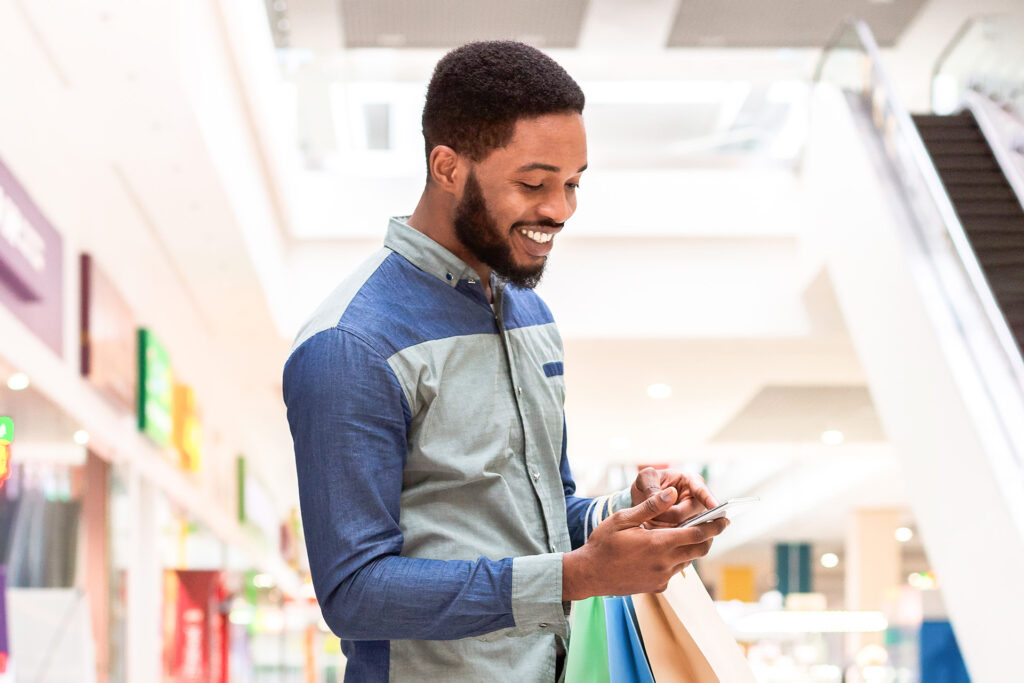 happy man shopping and looking at his phone